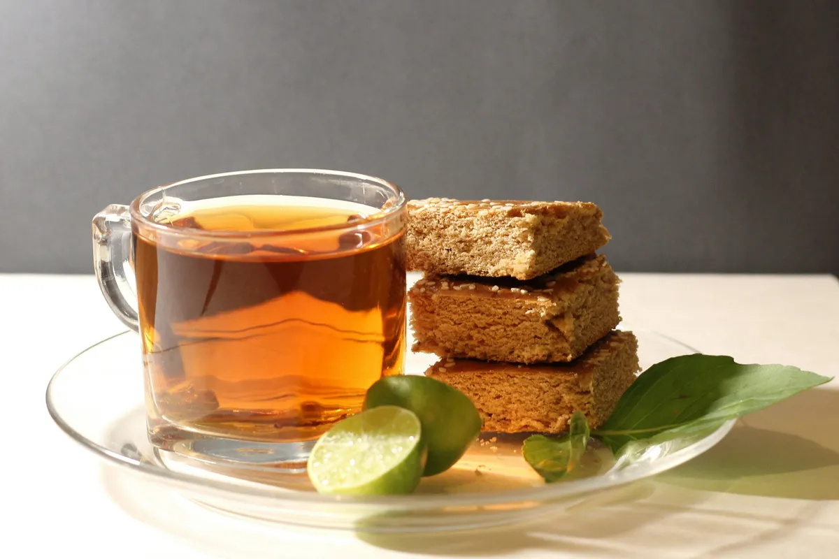 Xícara de chá quente com biscoitos e rodelas de limão sobre uma mesa